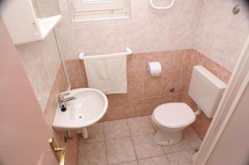La salle de bains est pourvue de toilettes blanches et d'un lavabo. dans l'établissement Apartments with a parking space Povljana, Pag - 233, à Povljana