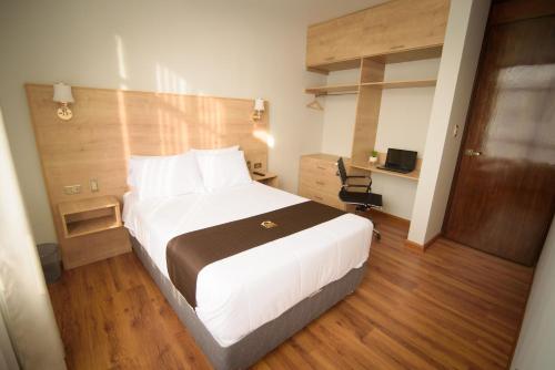 a bedroom with a large white bed and a chair at HOTEL PIEDRA SANTA - Moquegua in Moquegua
