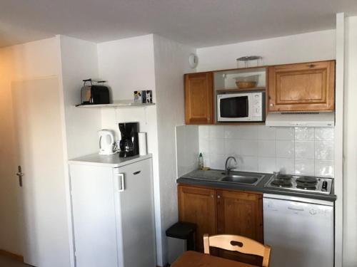 eine Küche mit einem weißen Kühlschrank und einer Mikrowelle in der Unterkunft Les toits de dévoluy in Le Dévoluy