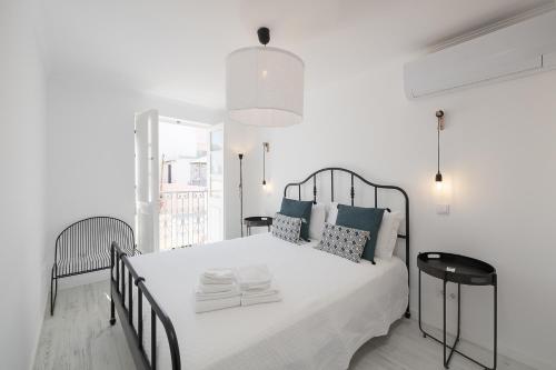 a white bedroom with a large bed with blue pillows at Travessa's House in Olhão