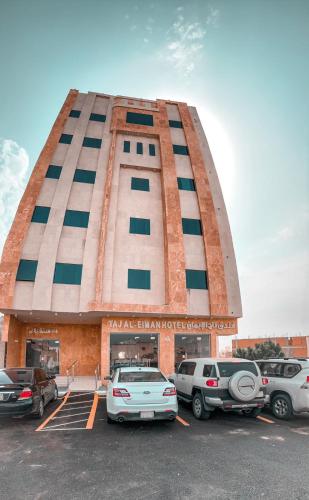 a building with cars parked in a parking lot at Taj Al Eiman Hotel in Al Madinah