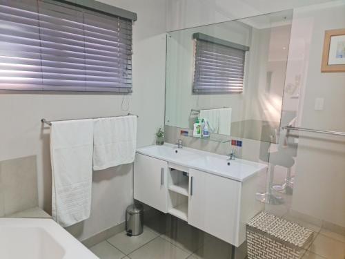 a white bathroom with a sink and a mirror at Africatamna Self Catering House in Durban