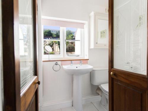 ein Badezimmer mit Waschbecken und Toilette und einem Fenster in der Unterkunft Catboat Cottage in Appledore