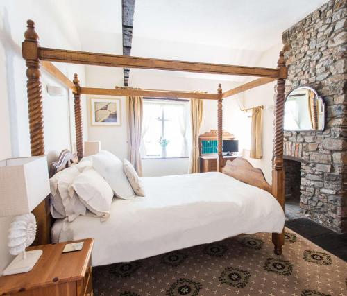 ein Schlafzimmer mit einem großen Bett und einer Steinwand in der Unterkunft Catboat Cottage in Appledore