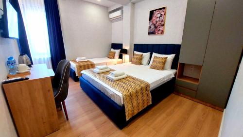 a hotel room with two beds and a desk at Falcon Boutique Hotel in Tbilisi City