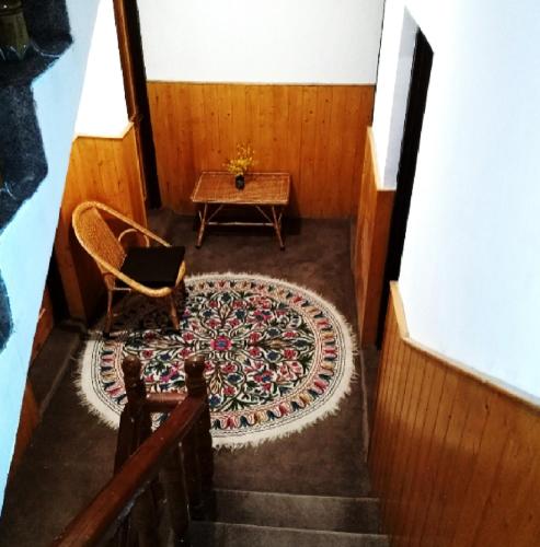 a staircase with a chair and a rug and a table at Cherrytree Resort in Srinagar