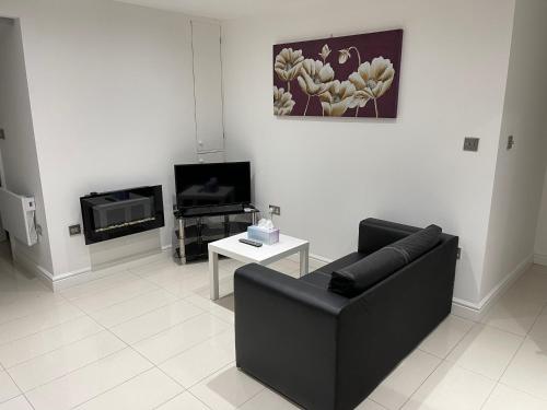 a living room with a black couch and a tv at Lovely 1-bedroom holiday home in Southminster in Southminster
