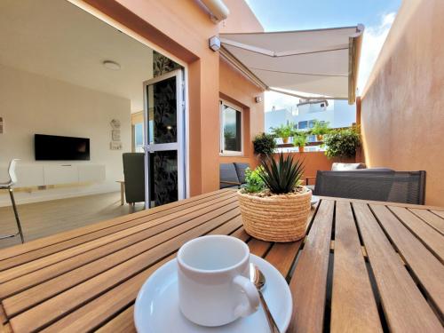 Una taza de café en una mesa de madera en la sala de estar. en The Valley View Apartments en La Orotava