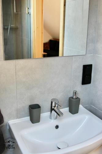 a bathroom sink with a mirror and a sink at Apartament Nad Zaporą in Szlembark