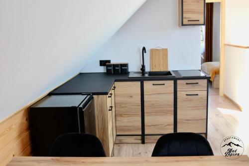 a kitchen with a counter and a sink and a staircase at Apartament Nad Zaporą in Szlembark