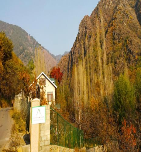 a house in front of a mountain with a fence at Cherrytree Resort in Srinagar