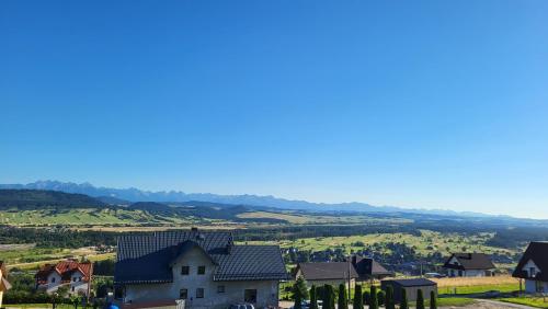 a house in a village with mountains in the background at Apartament Nad Zaporą in Szlembark