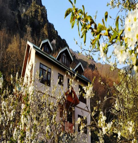 a white house with a mountain in the background at Cherrytree Resort in Srinagar
