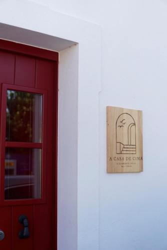 un panneau sur un mur à côté d'une porte rouge dans l'établissement A Casa de Cima - Cacela Velha, à Vila Nova De Cacela