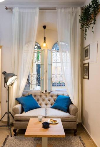 a living room with a couch with blue pillows and a table at Ovadia Somech #1 in Jerusalem