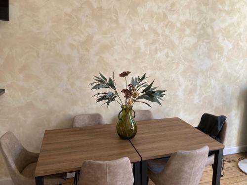 a vase with flowers on a wooden table with chairs at Appartement cosy au cœur de la ville d’été in Arcachon