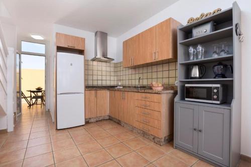 La cuisine est équipée d'un réfrigérateur blanc et de placards en bois. dans l'établissement Los Majos Fuerteventura, à Tarajalejo