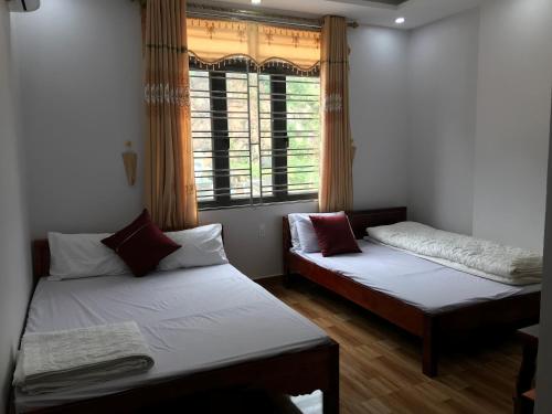 Duas camas num quarto com uma janela em Nhà Nghỉ Minh Hảo em Làng Môn