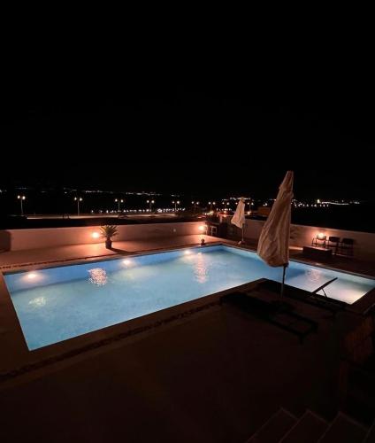 a swimming pool at night with an umbrella at Follow Sea Villa in Sowayma