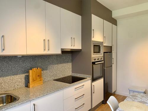 a kitchen with white cabinets and stainless steel appliances at N&E - Home Celanova AVD San Rosendo in Celanova