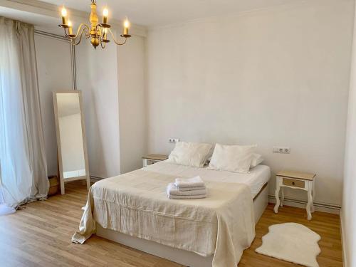 Un dormitorio con una cama con sábanas blancas y una lámpara de araña. en N&E - Home Celanova AVD San Rosendo, en Celanova