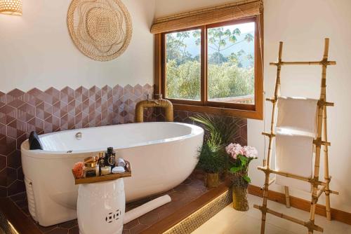 a bathroom with a white tub and a window at Embaúba Boutique Hotel in Teresópolis