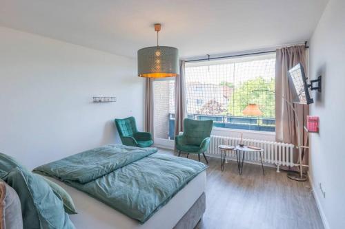 um quarto com uma cama, 2 cadeiras e uma janela em Apartment im Herzen von Braunschweig mit Parkplatz em Braunschweig