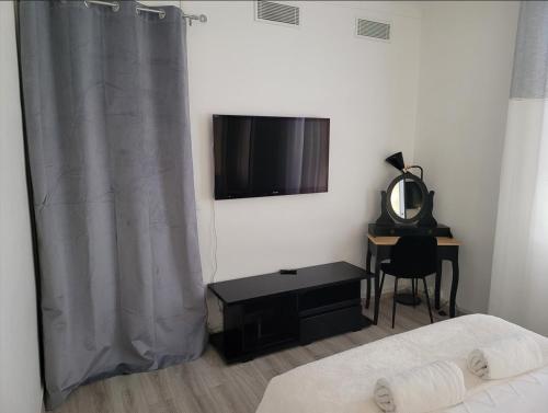a bedroom with a bed and a television and a desk at 1 Chambre paisible à La Trinité proche de Nice et Monaco in La Trinité