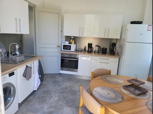 uma cozinha com uma mesa e um frigorífico branco em 1 Chambre paisible à La Trinité proche de Nice et Monaco em La Trinité