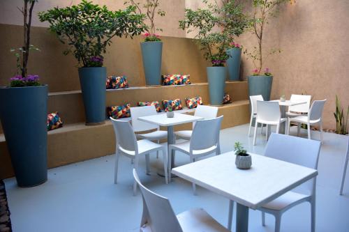 a restaurant with white tables and chairs and potted plants at ian Hotel in Buenos Aires