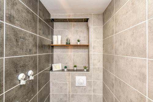 La salle de bains est pourvue d'une douche carrelée et d'une étagère. dans l'établissement Le Petit Parfait Confort Gare Hamac Netflix, à Grenoble