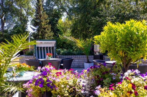 a garden with tables and chairs and flowers at Hotel Blinkfüer in Dierhagen