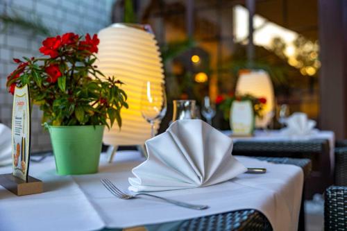 a table with a napkin on a table with a lamp and flowers at Hotel Blinkfüer in Dierhagen