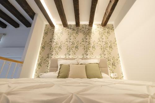 - une chambre avec un lit blanc et un papier peint floral dans l'établissement Precioso Loft en Centro Histórico de Córdoba., à Cordoue