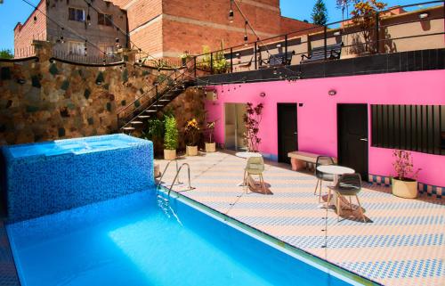 a swimming pool with chairs and a pink building at HOTEL BRANA in Medellín