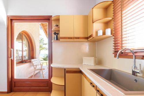 eine Küche mit einem Waschbecken und einem Fenster in der Unterkunft Luna Villa Private Beach in Nea Iraklia