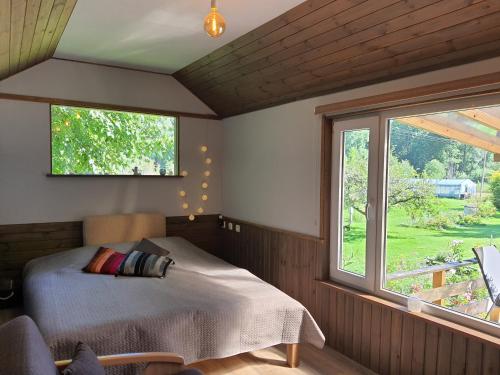 a bedroom with a bed and a large window at Atpūta namiņā pie jūras Skujiņas in Lembuži