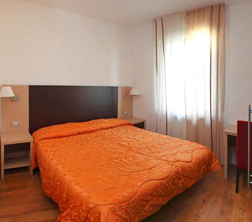 a bedroom with a bed with an orange comforter at Il Garibaldi in San Quirico dʼOrcia