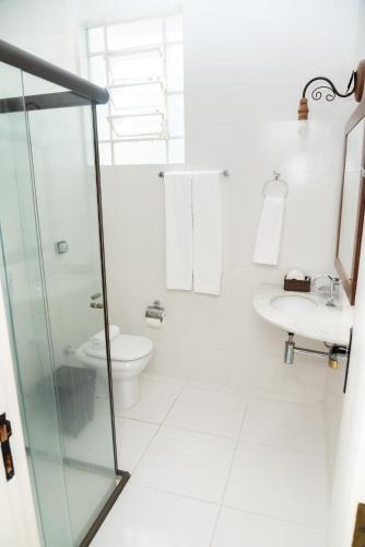 Un baño blanco con inodoro y lavabo. en Pousada Águas de Caxambu, en Caxambu