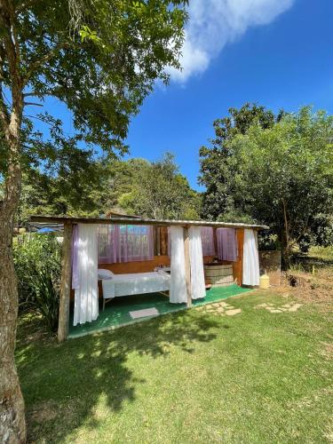 a house with a bed and curtains in a yard at Pousada Alquimia in Aiuruoca