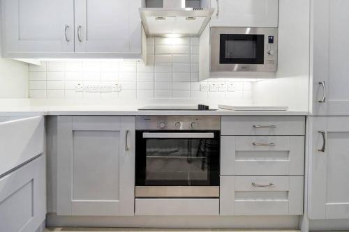 a white kitchen with a stove and a microwave at HillTop View 'Sleeping 5 guests' in Derry Londonderry