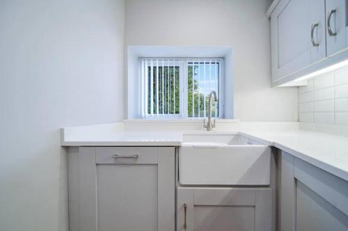 a white kitchen with a sink and a window at HillTop View 'Sleeping 5 guests' in Derry Londonderry