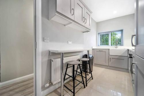 a kitchen with white cabinets and bar stools at HillTop View 'Sleeping 5 guests' in Derry Londonderry