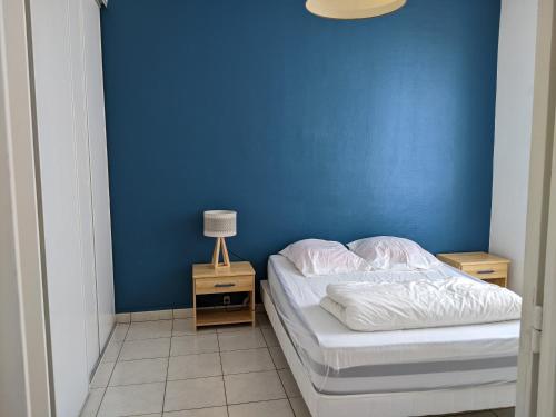 een blauwe slaapkamer met een bed en een nachtkastje met een lamp bij Fouras - T2 Hyper centre les pieds dans le sable ! in Fouras