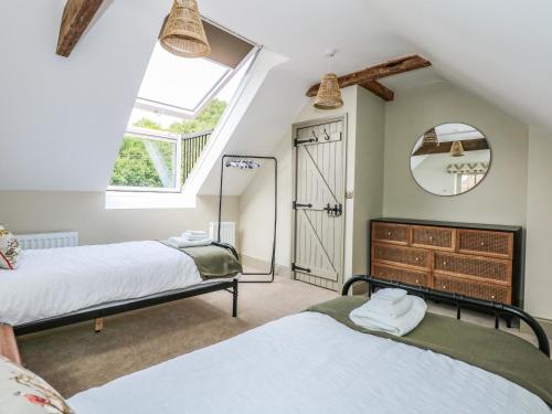 two beds in a room with a window and a mirror at The Stable at Warren House in Market Rasen