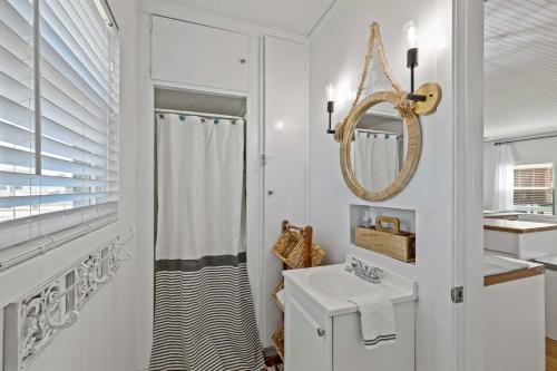 Baño blanco con lavabo y espejo en Bright Jamaica Beach Getaway Less Than 1 Mi to Shore!, en Galveston