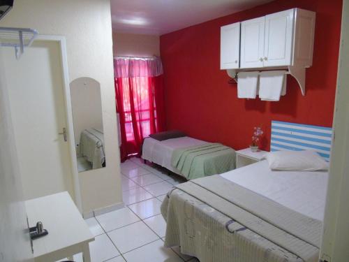 a bedroom with two beds and a red wall at Visk Palace Hotel e Restaurante in Foz do Iguaçu