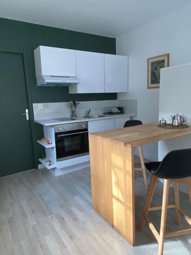 une cuisine avec des placards blancs et une table en bois dans l'établissement Studio climatisé dans un ancien domaine viticole, à Montpellier