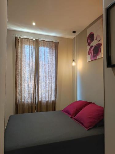 - une chambre avec un lit doté d'un oreiller rouge et d'une fenêtre dans l'établissement Chambres Supérieures privées, plein centre-ville de Nice - HUBERT, à Nice