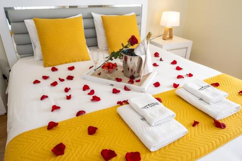 a bed with red roses and towels on it at Villa Tavares Suítes in Arouca